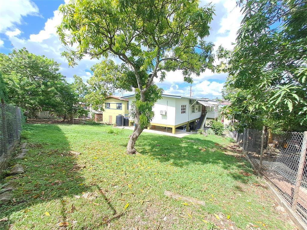 A grassy backyard features a large tree and a white house on stilts — 21 Southern Main Road Duncan Village, FL