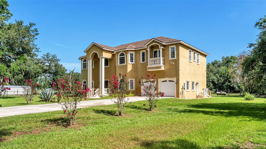 A two-story, tan-colored house with a columned entryway and a two-car garage — 1282 MCGEE ROAD, PLANT CITY, FL