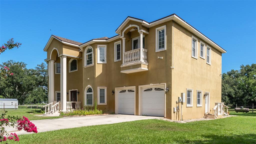 A two-story tan stucco house with a two-car garage and a front balcony — 1282 MCGEE ROAD, PLANT CITY, FL