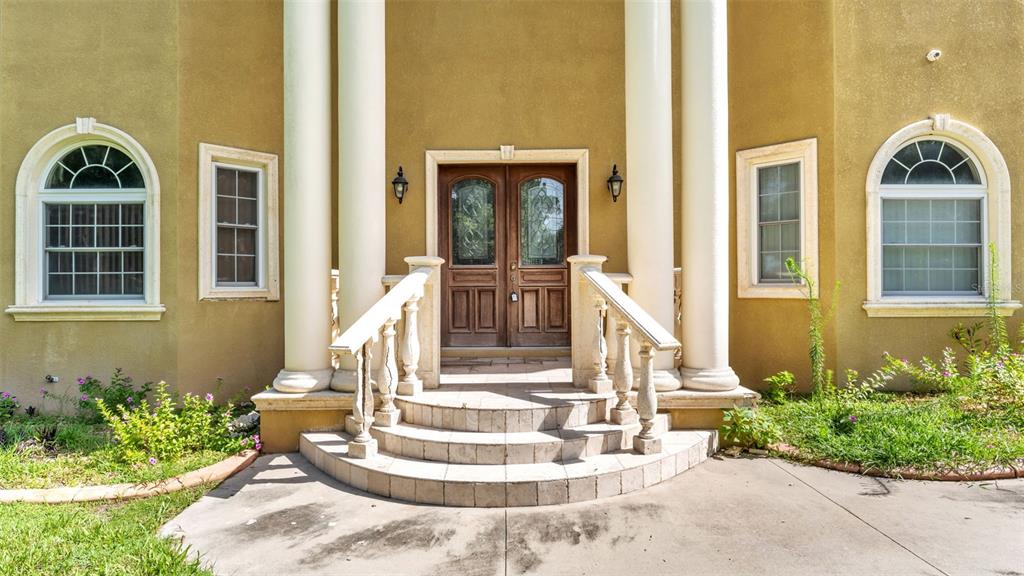 The exterior of a house features a double front door, columns, and arched windows — 1282 MCGEE ROAD, PLANT CITY, FL