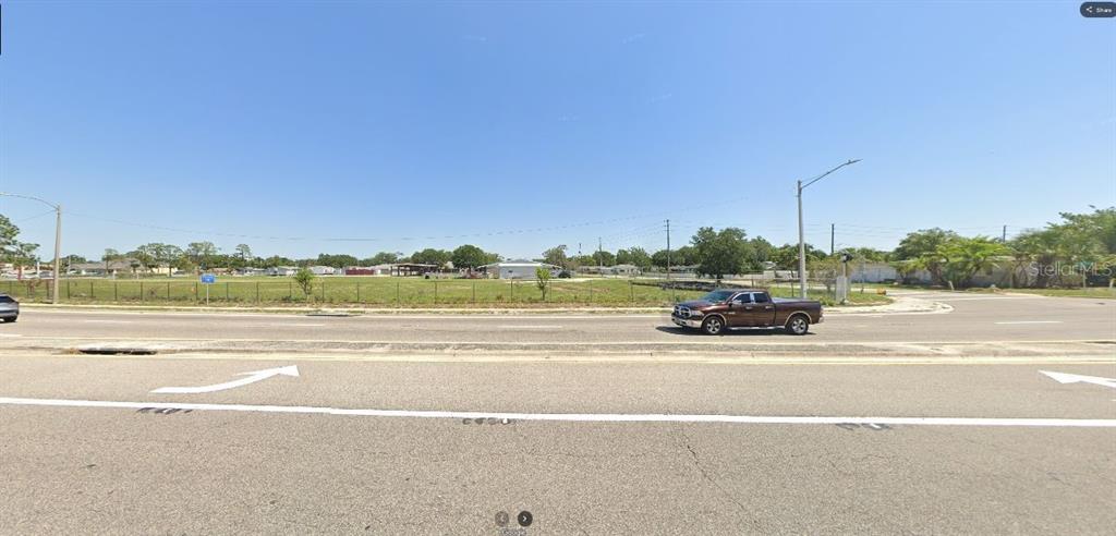 A brown pickup truck drives past a large, flat, grassy vacant lot — HWY 60 E, LAKE WALES, FL
