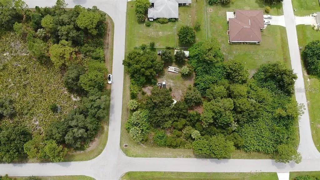 An aerial view shows a vacant, wooded residential lot situated between two paved roads — 21360 WICKER AVENUE, PORT CHARLOTTE, FL