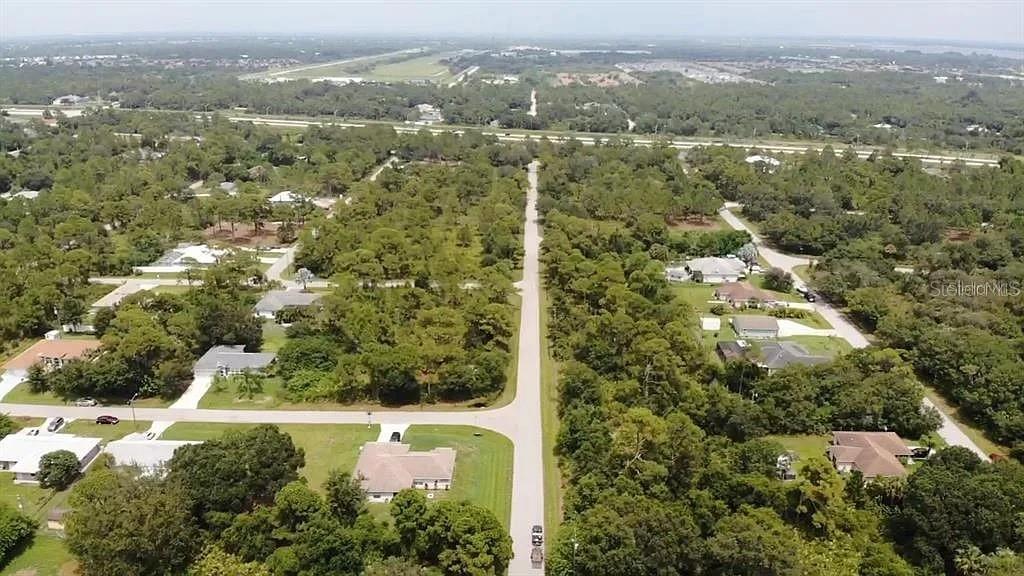 An aerial view shows a residential street lined with houses and trees in a neighborhood — 21360 WICKER AVENUE, PORT CHARLOTTE, FL