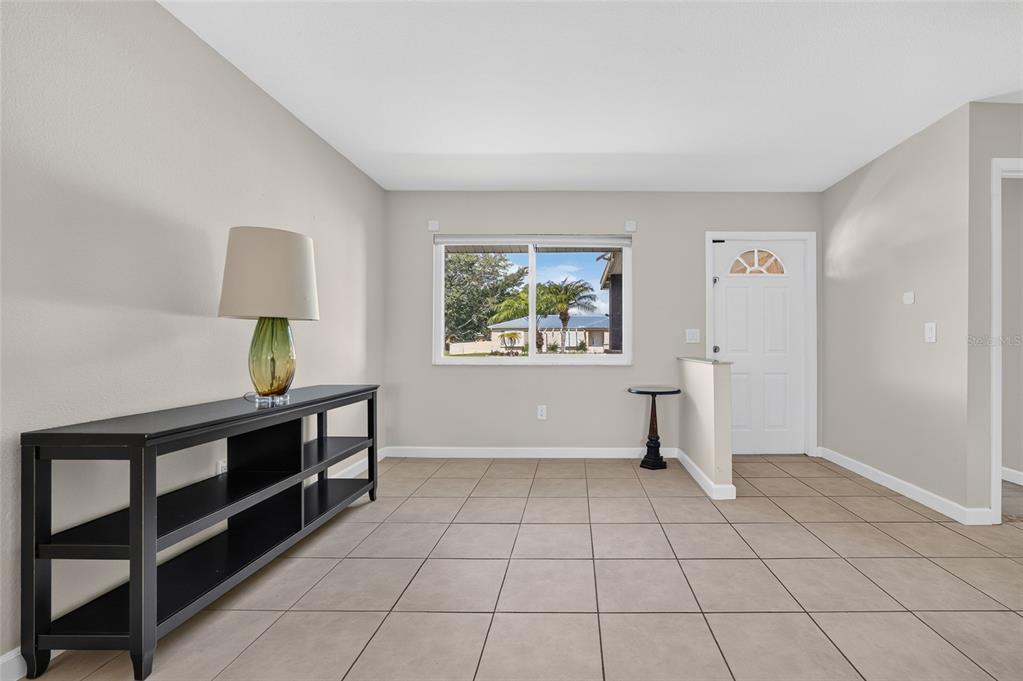 A room with light walls, tile flooring, a black console table, and a front door — 7582 LYNCREST STREET, NORTH PORT, FL