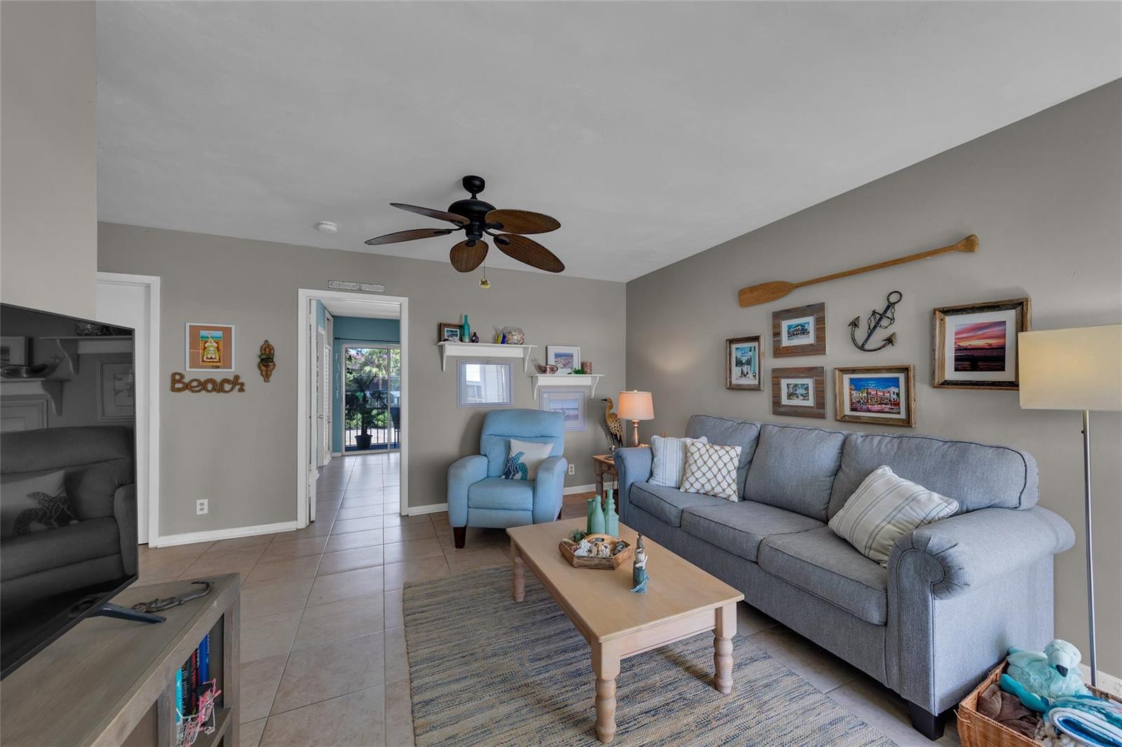 A living room features a grey sofa, light blue armchair, coffee table, and coastal-themed wall decor — 11 SW 4th Avenue # 11, Boca Raton FL 33432, BOCA RATON, FL