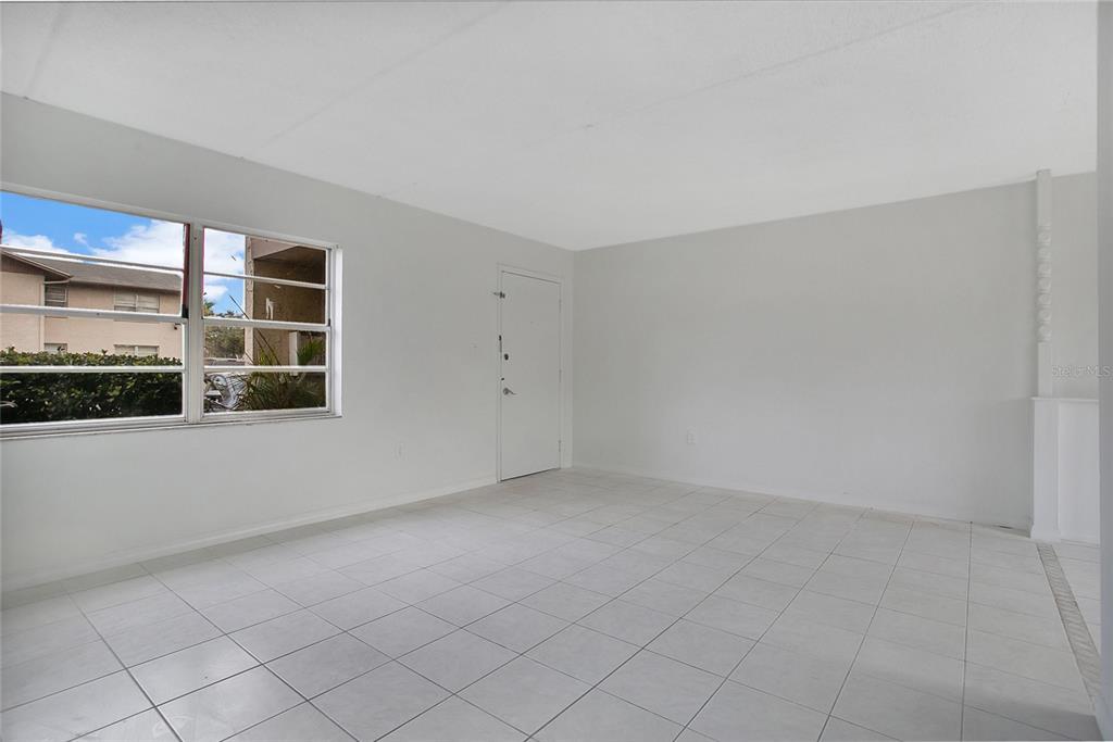 An empty room features white walls, white tile flooring, and a window overlooking a building — 1914 HONOUR ROAD UNIT 2, ORLANDO, FL