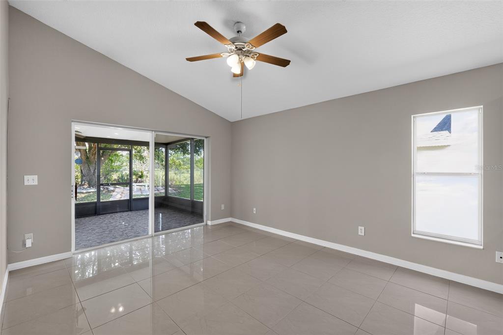 An empty room with gray walls, large light-colored floor tiles, a ceiling fan, and sliding doors — 4027 LONGWORTH LOOP, KISSIMMEE, FL