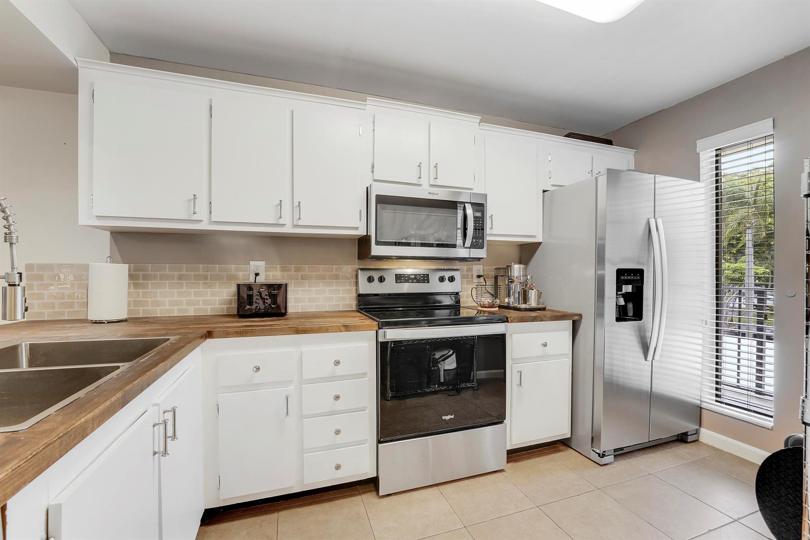 A kitchen features white cabinets, butcher block countertops, stainless steel appliances, and a tile backsplash — 20 Royal Palm Way # 204, Boca Raton FL 33432, BOCA RATON, FL