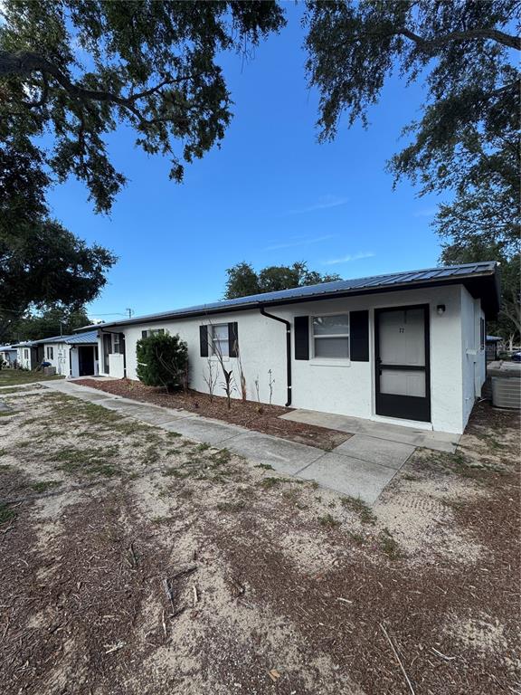 A single-story white stucco building with a dark metal roof and a screen door — 455 S BUCKMOORE ROAD UNIT 72, LAKE WALES, FL