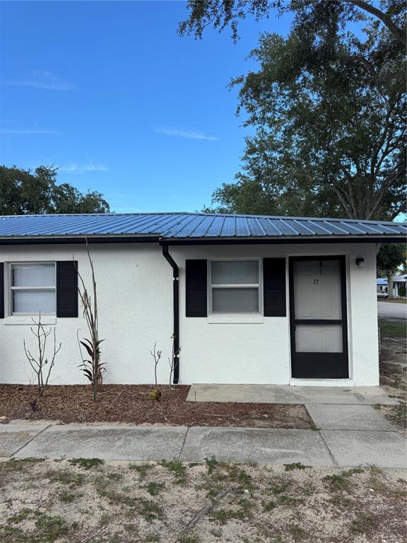 A single-story white stucco building features a blue metal roof and black window shutters — 455 S BUCKMOORE ROAD UNIT 72, LAKE WALES, FL