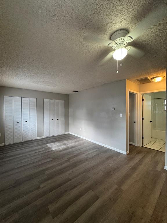 A bedroom with gray wood-look flooring, white louvered closet doors, and a ceiling fan — 455 S BUCKMOORE ROAD UNIT 72, LAKE WALES, FL