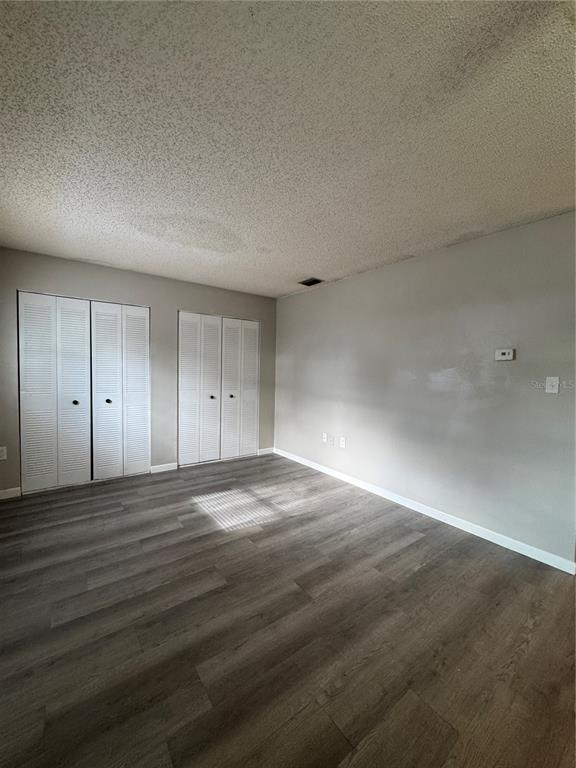 An empty bedroom features gray walls, wood-look flooring, and two sets of white louvered closet doors — 455 S BUCKMOORE ROAD UNIT 72, LAKE WALES, FL