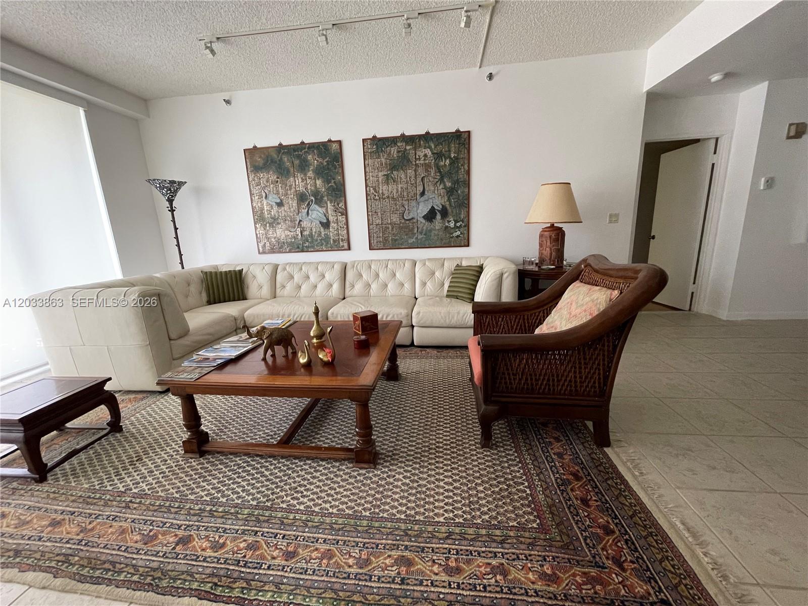 A living room features a large white sectional sofa, a wooden coffee table, and patterned rug — 251 Crandon Blvd # 338, Key Biscayne FL 33149, KEY BISCAYNE, FL