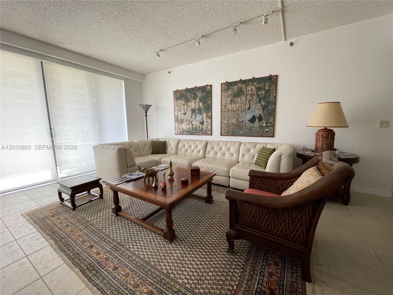 A living room features a white sectional sofa, a wooden coffee table, and patterned area rug — 251 Crandon Blvd # 338, Key Biscayne FL 33149, KEY BISCAYNE, FL