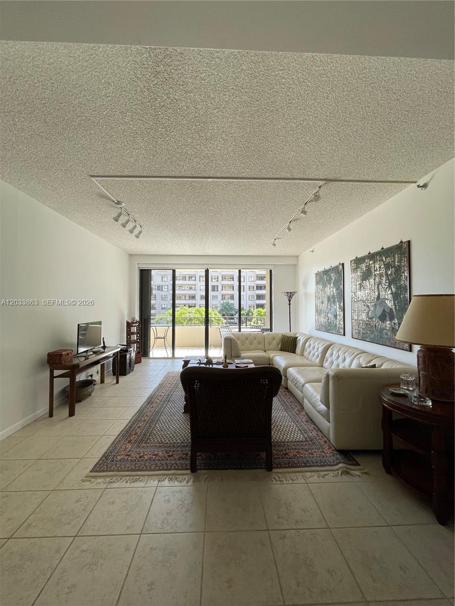 A living room features a white sectional sofa, a patterned rug, and a balcony view — 251 Crandon Blvd # 338, Key Biscayne FL 33149, KEY BISCAYNE, FL