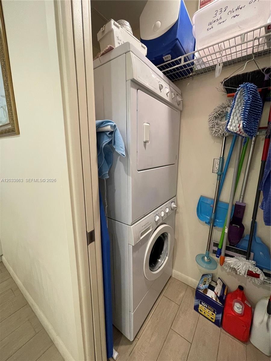 A stacked washer and dryer unit sits in a small closet with cleaning supplies — 251 Crandon Blvd # 338, Key Biscayne FL 33149, KEY BISCAYNE, FL