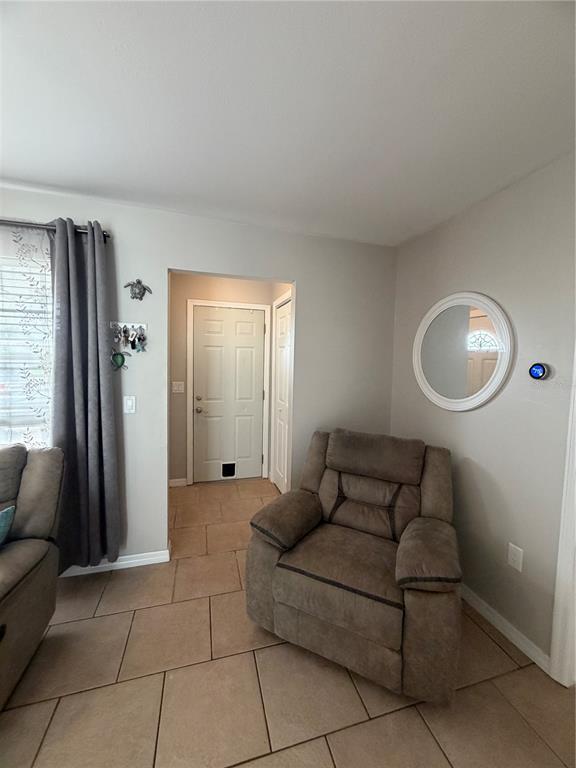 A living area features a brown recliner, tiled flooring, and a doorway leading to an entryway — 820 SAN SALVADOR DRIVE, DUNEDIN, FL