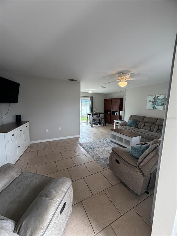 A living room with tile floors, a sectional sofa, and a dining area beyond — 820 SAN SALVADOR DRIVE, DUNEDIN, FL