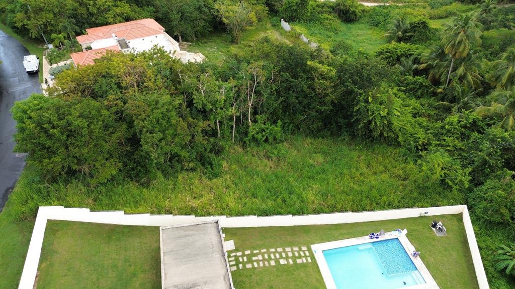 An aerial view shows a vacant, grassy lot situated between two residential properties with pools — 39 COCOLOBA UNIT 39, HUMACAO, PR