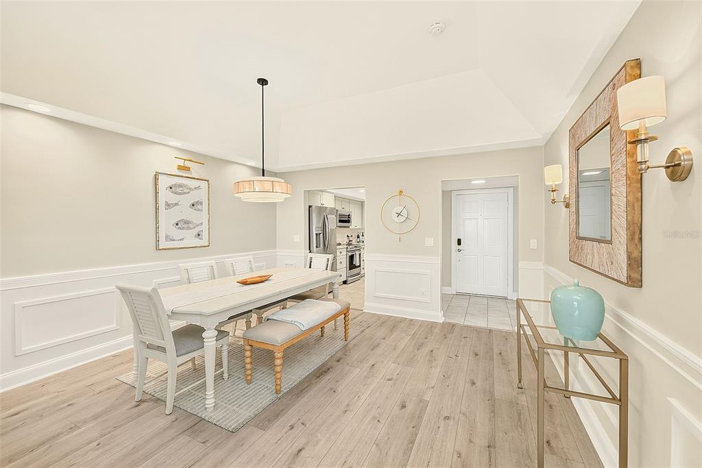 A dining room with a white table, bench seating, light wood floors, and wall molding — 147 BLUFF VIEW DRIVE UNIT 304, LARGO, FL