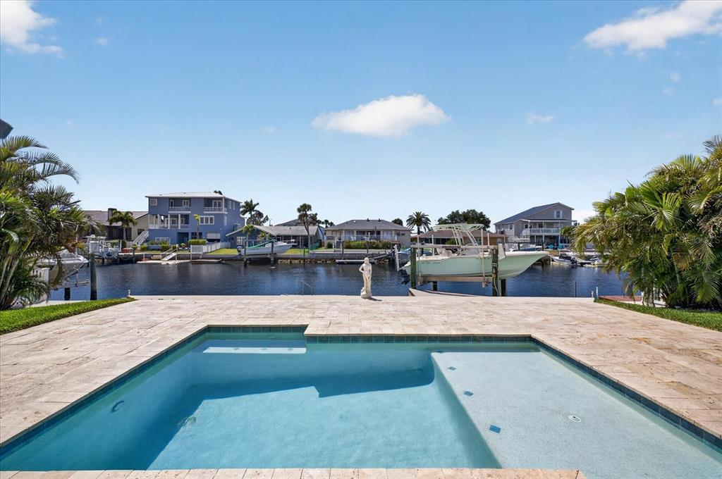 A swimming pool sits on a stone patio overlooking a canal with docked boats — 5101 SOUTH SHORE DRIVE, NEW PORT RICHEY, FL