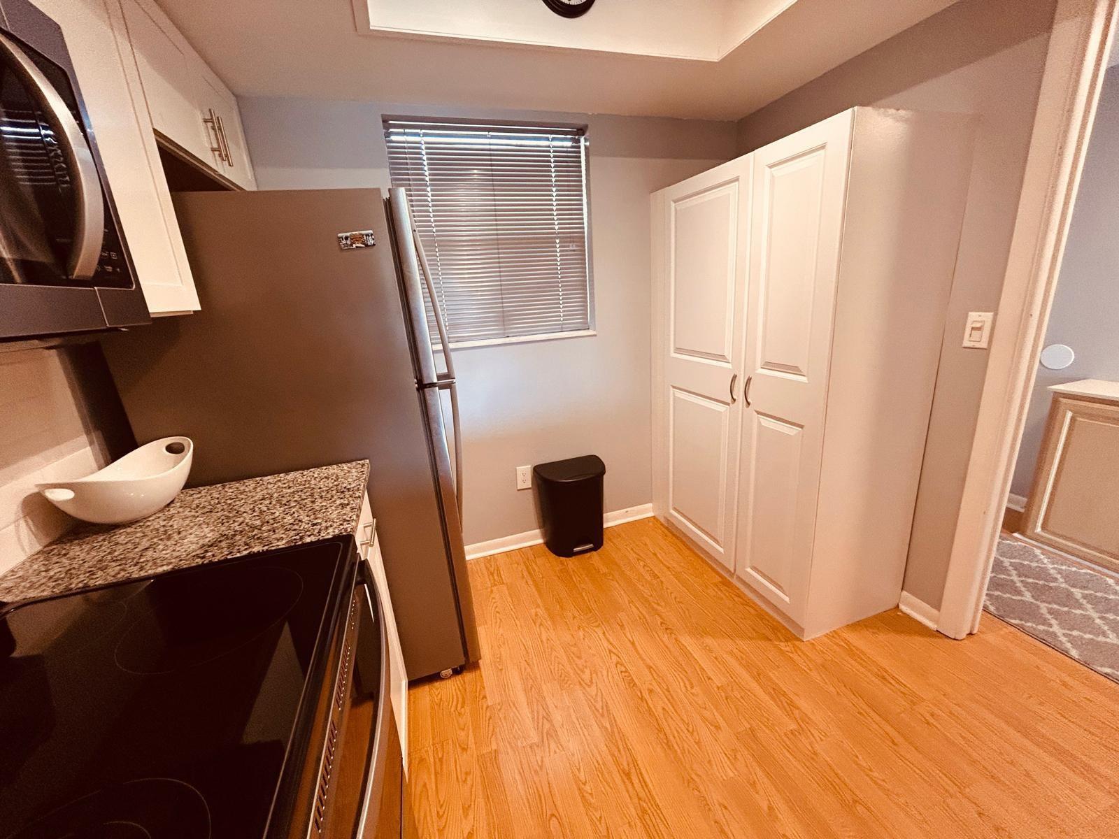 A kitchen features stainless steel appliances, white cabinetry, granite countertops, and light wood flooring — 2050 Oleander Boulevard # 703, Fort Pierce FL 34950, FORT PIERCE, FL