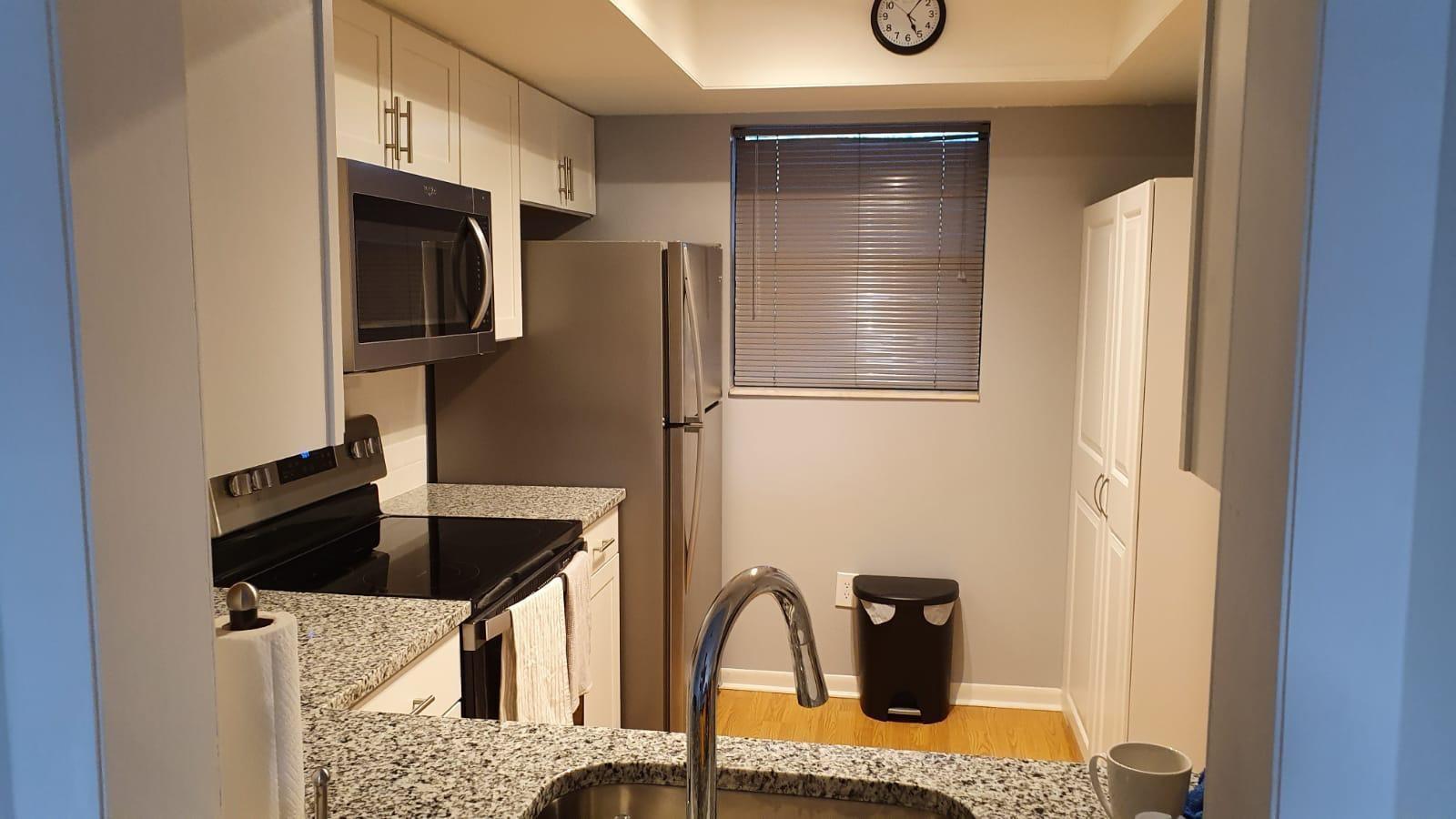 A kitchen features white cabinets, granite countertops, stainless steel appliances, and a window with blinds — 2050 Oleander Boulevard # 703, Fort Pierce FL 34950, FORT PIERCE, FL