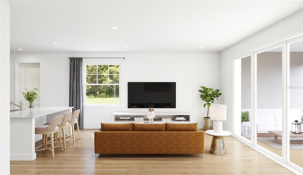 This is a digital rendering of a living room featuring a brown sofa and kitchen island — 10040 BLACKSTONE CREEK COURT Aster, RIVERVIEW, FL