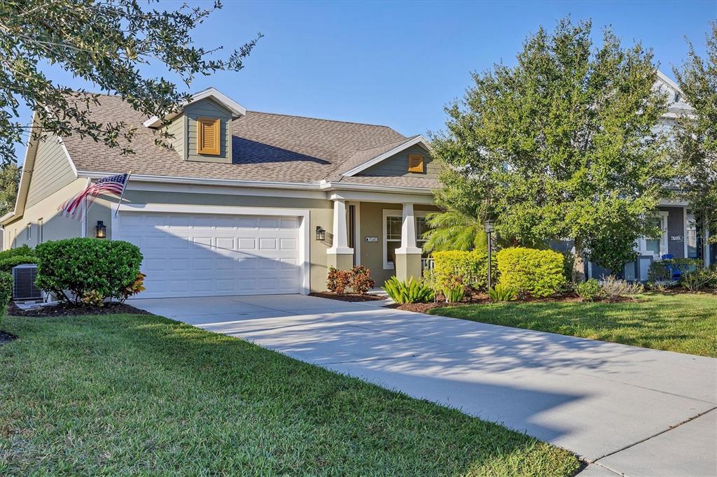 A single-story house with a two-car garage, light green siding, and a concrete driveway — 7040 WHITE WILLOW COURT, SARASOTA, FL
