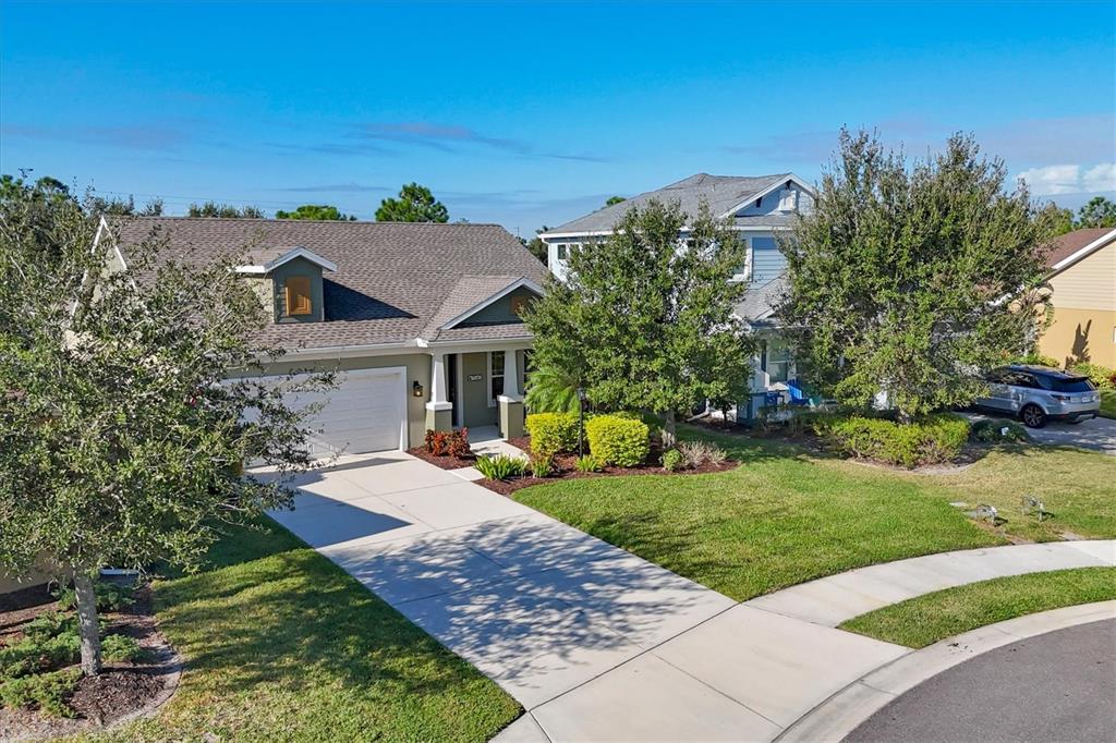 An aerial view shows a single-story house with a driveway and a neighboring two-story home — 7040 WHITE WILLOW COURT, SARASOTA, FL