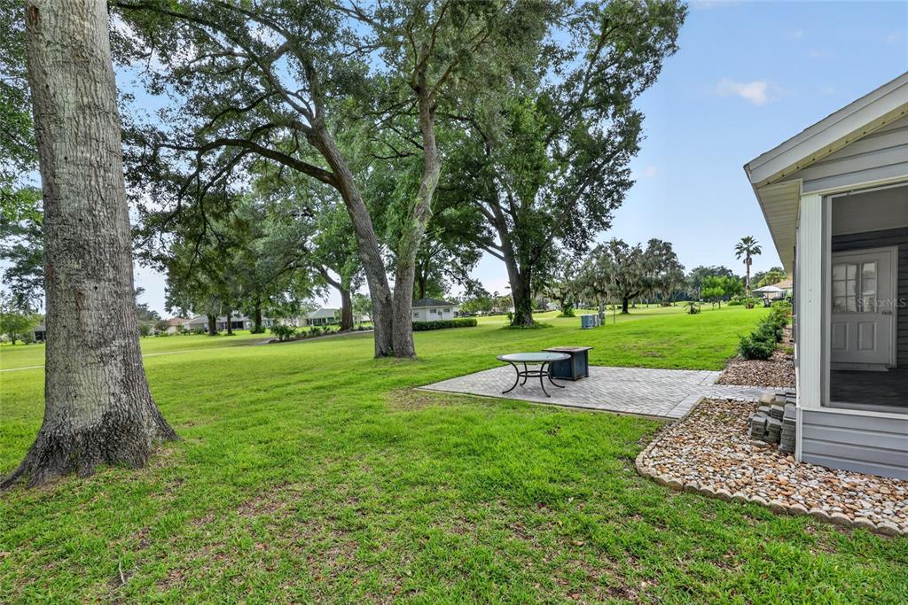 A paved patio sits on a grassy lawn next to a house with a screened porch — 14845 SW 112TH CIRCLE, DUNNELLON, FL