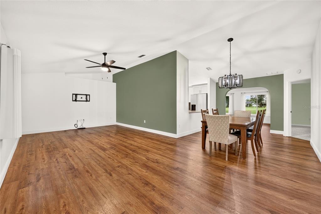 A living and dining area with wood-look flooring, white walls, and a green accent wall — 14845 SW 112TH CIRCLE, DUNNELLON, FL