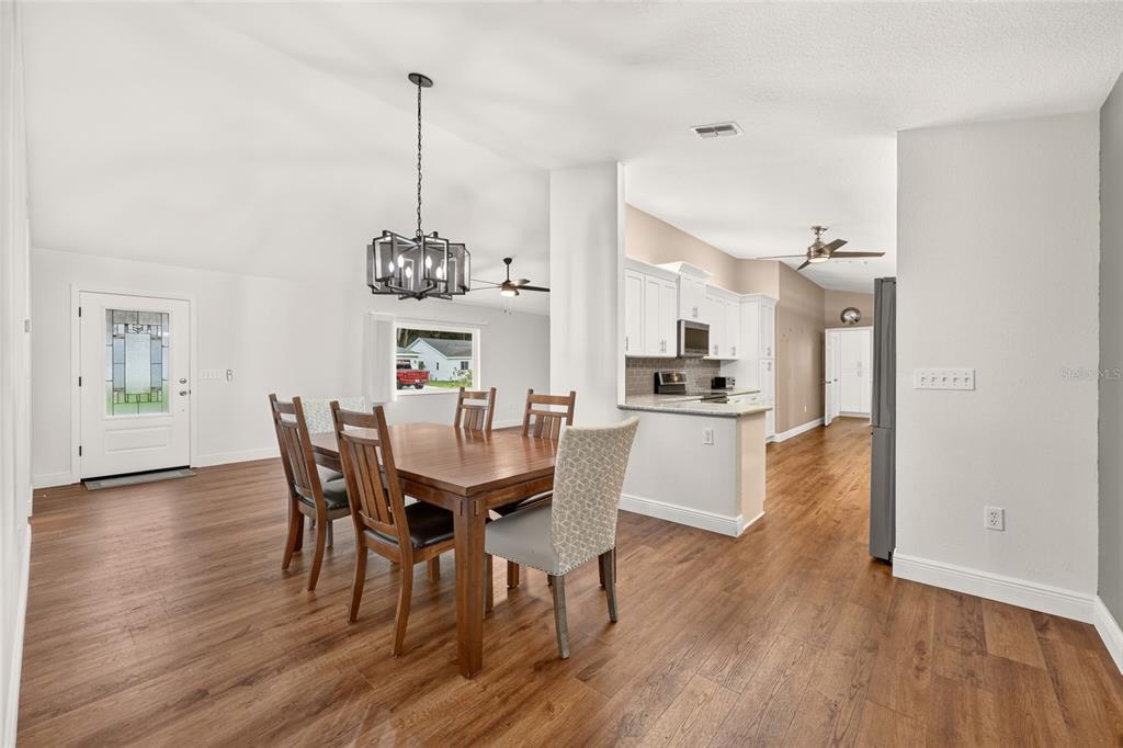 A dining area with a wooden table and chairs sits adjacent to a white kitchen — 14845 SW 112TH CIRCLE, DUNNELLON, FL