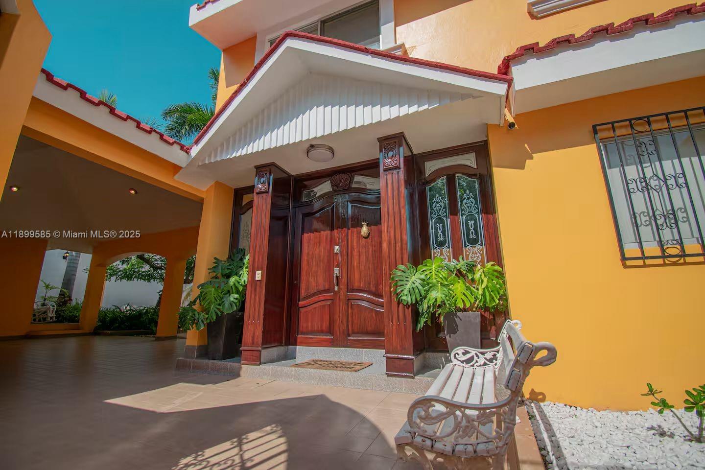 The exterior features a wooden double door entrance with a white bench and orange walls — 1010 La Joya, WY 82110, WY
