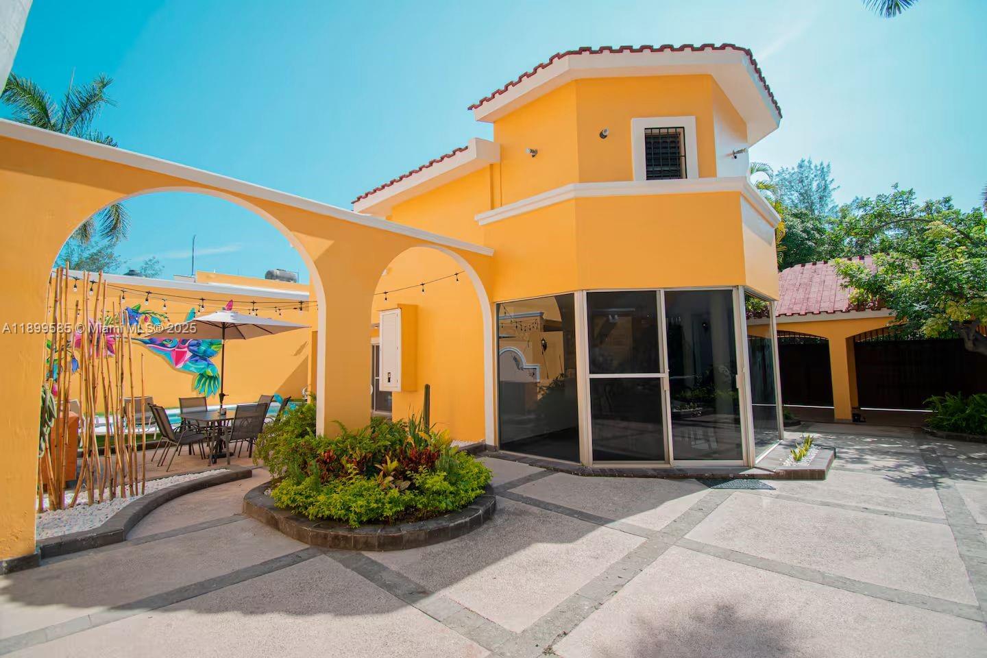 A yellow two-story house features a patio with a dining set and a pool — 1010 La Joya, WY 82110, WY