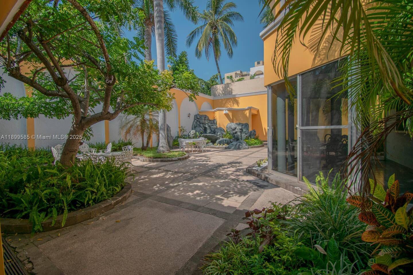 A paved patio features a rock garden, outdoor seating, and lush landscaping beside a house — 1010 La Joya, WY 82110, WY