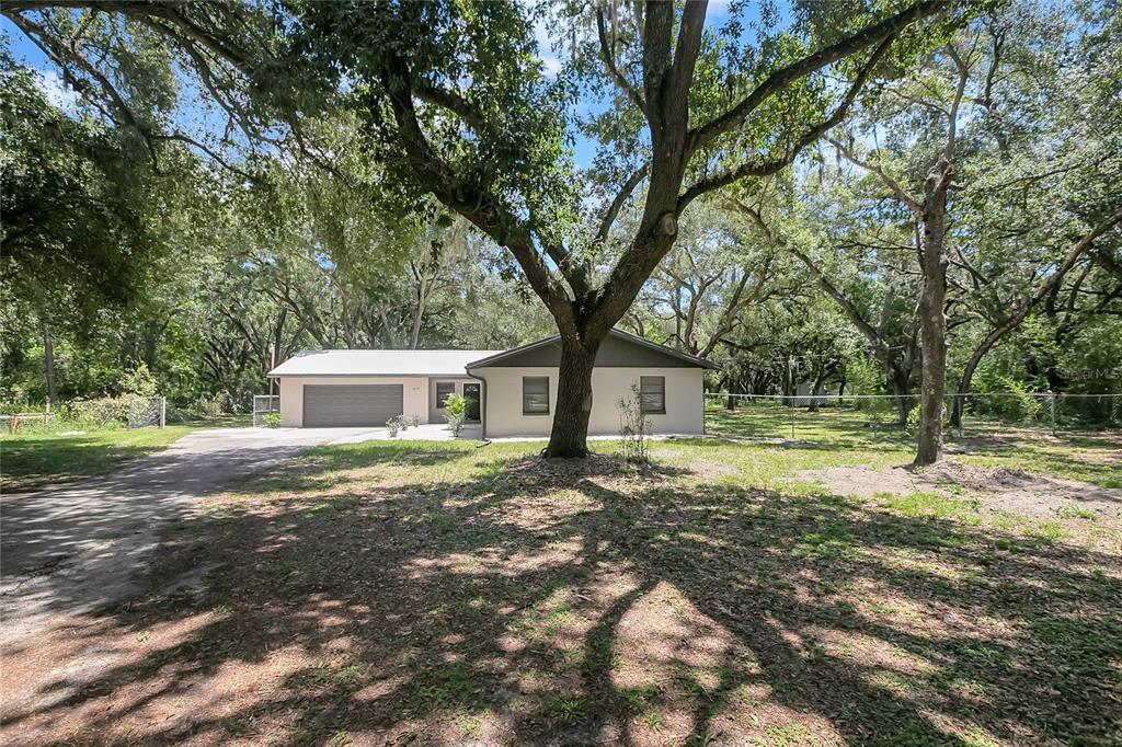 A single-story house with a garage sits on a wooded lot under large oak trees — 1609 ITCHEPACKESASSA DRIVE, LAKELAND, FL