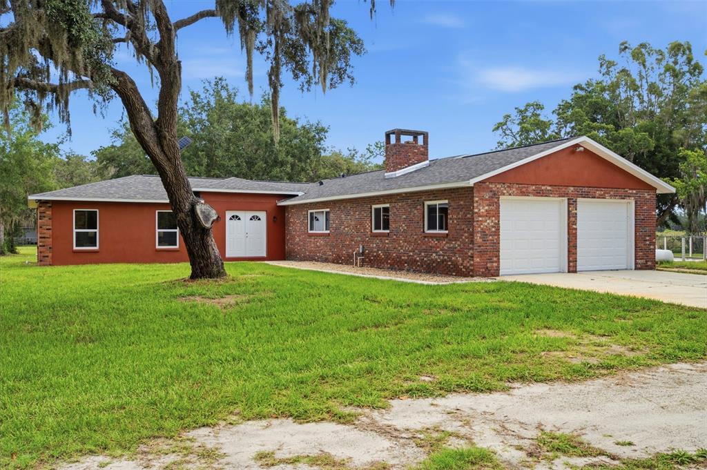 A single-story brick and stucco house with a two-car garage and a large oak tree — 10115 FRIERSON LAKE DRIVE, HUDSON, FL