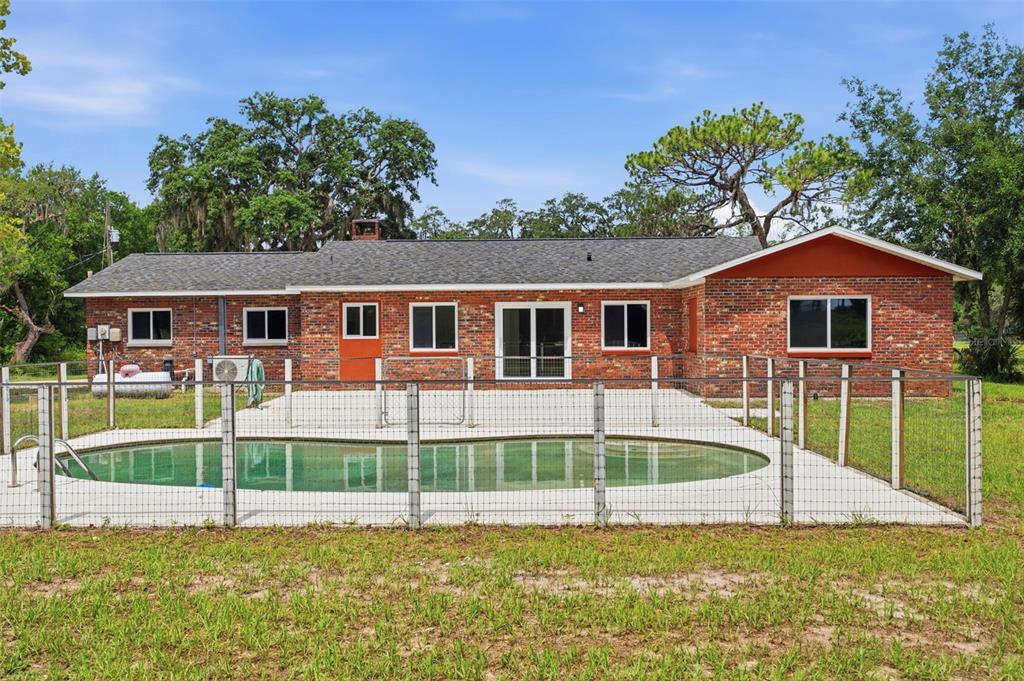 A brick house with a fenced-in swimming pool and patio in a grassy backyard — 10115 FRIERSON LAKE DRIVE, HUDSON, FL