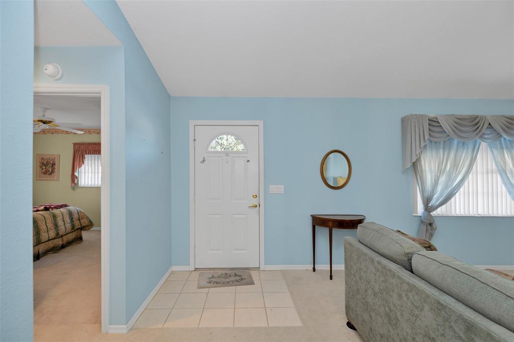 An entryway with a white door, tiled floor, and light blue walls leads to a bedroom — 9921 SE 138TH LOOP, SUMMERFIELD, FL
