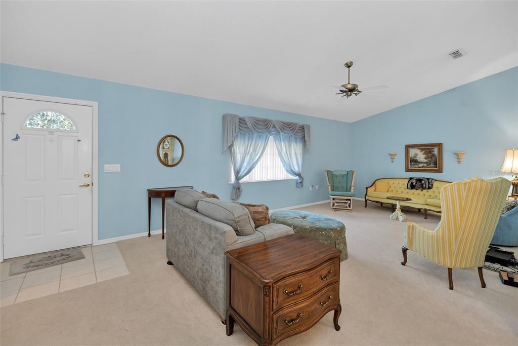 A living room with light blue walls, beige carpeting, and traditional furniture — 9921 SE 138TH LOOP, SUMMERFIELD, FL