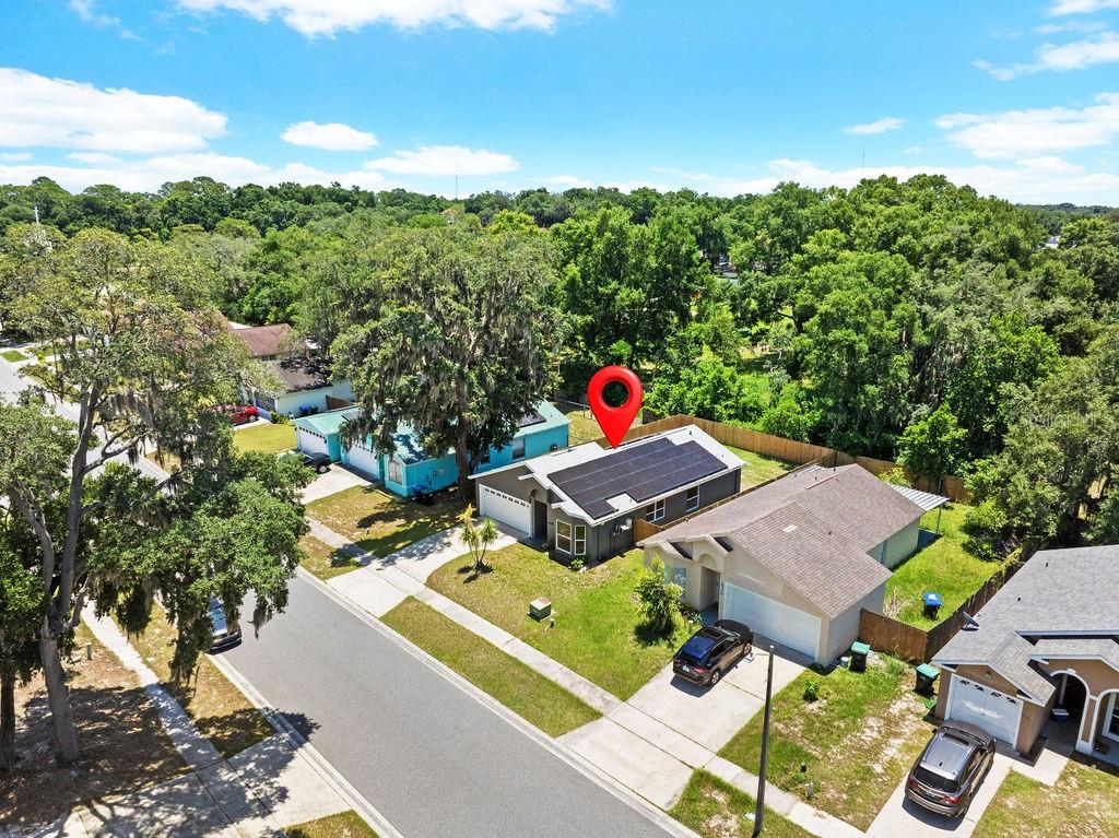 An aerial view shows a suburban house with solar panels on the roof and a driveway — 6330 RUTHIE DRIVE, ORLANDO, FL