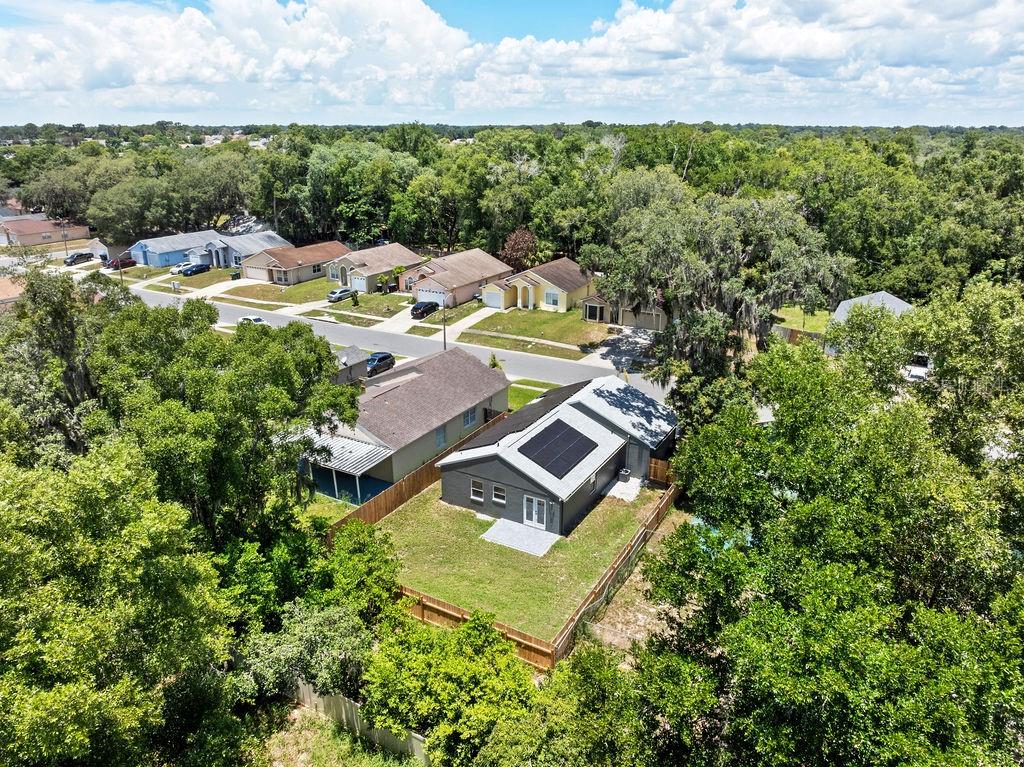 An aerial view shows a gray house with solar panels on its roof and a fenced yard — 6330 RUTHIE DRIVE, ORLANDO, FL