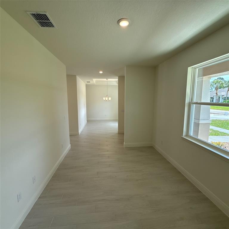 A bright, empty room with light wood-look tile flooring and a view of the neighborhood — 106 FORRESTER PLACE, PALM COAST, FL