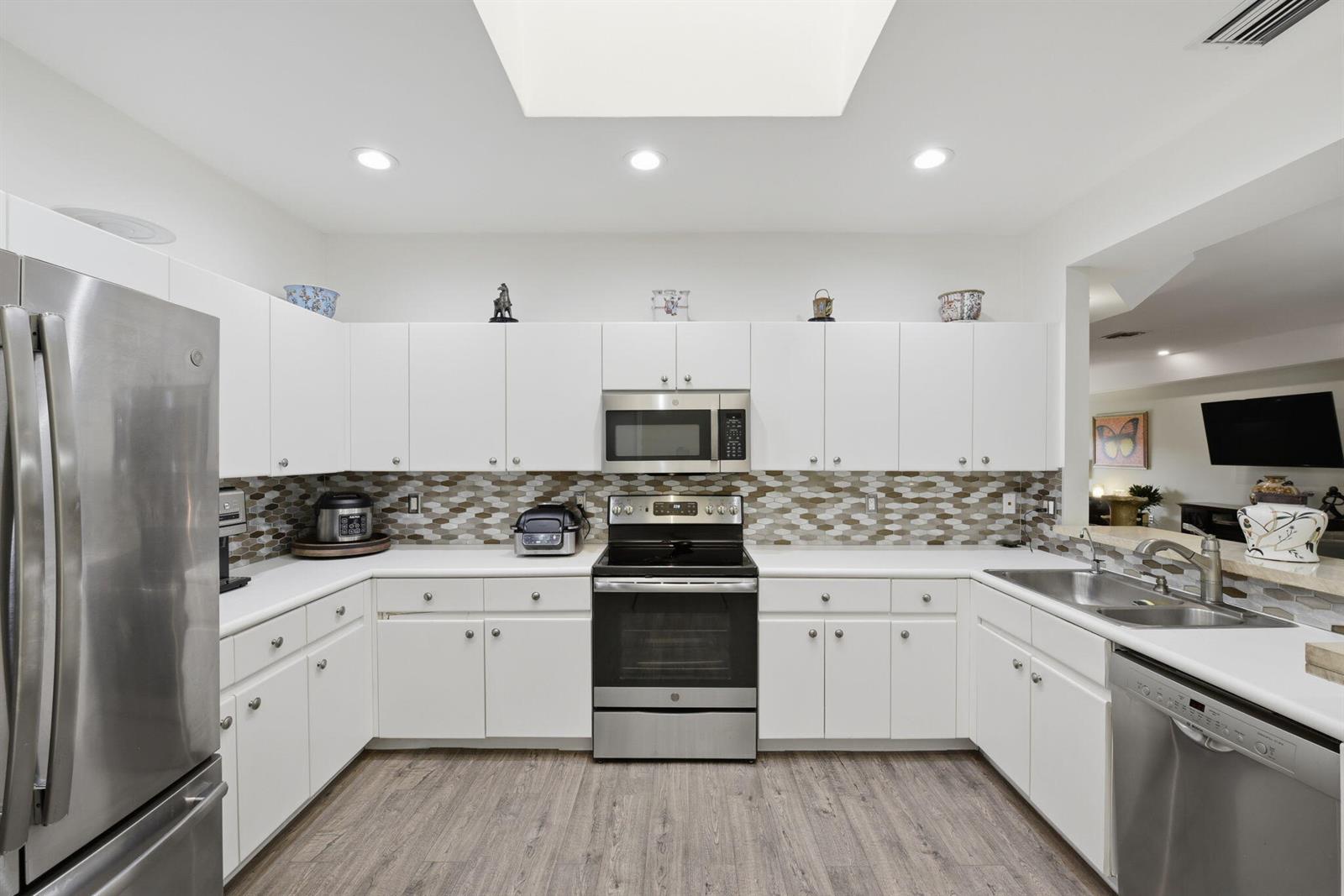 A kitchen with white cabinets, stainless steel appliances, and a hexagonal tile backsplash — 9857 Summerbrook Terrace # B, Boynton Beach FL 33437, BOYNTON BEACH, FL