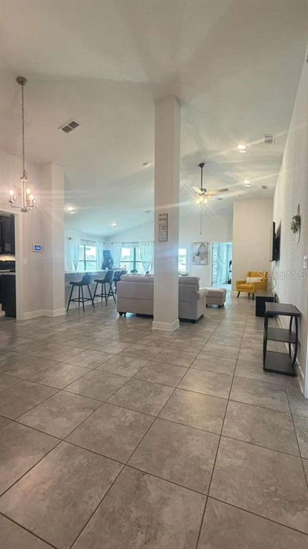 A spacious open-concept living room features light tile flooring, a central pillar, and vaulted ceilings — 365 CITRUS POINTE DRIVE, DAVENPORT, FL