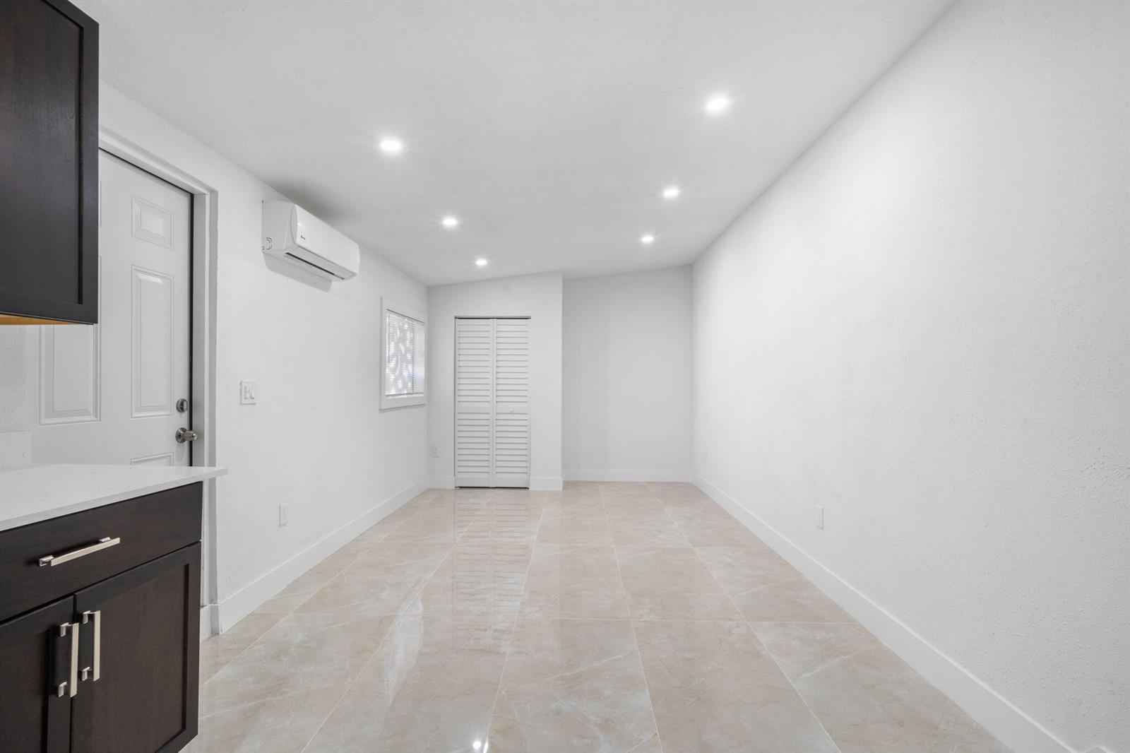 A bright, empty room features white walls, recessed lighting, tile flooring, and a wall-mounted air conditioner — 1300 NW 90th Street, Miami FL 33147, MIAMI, FL