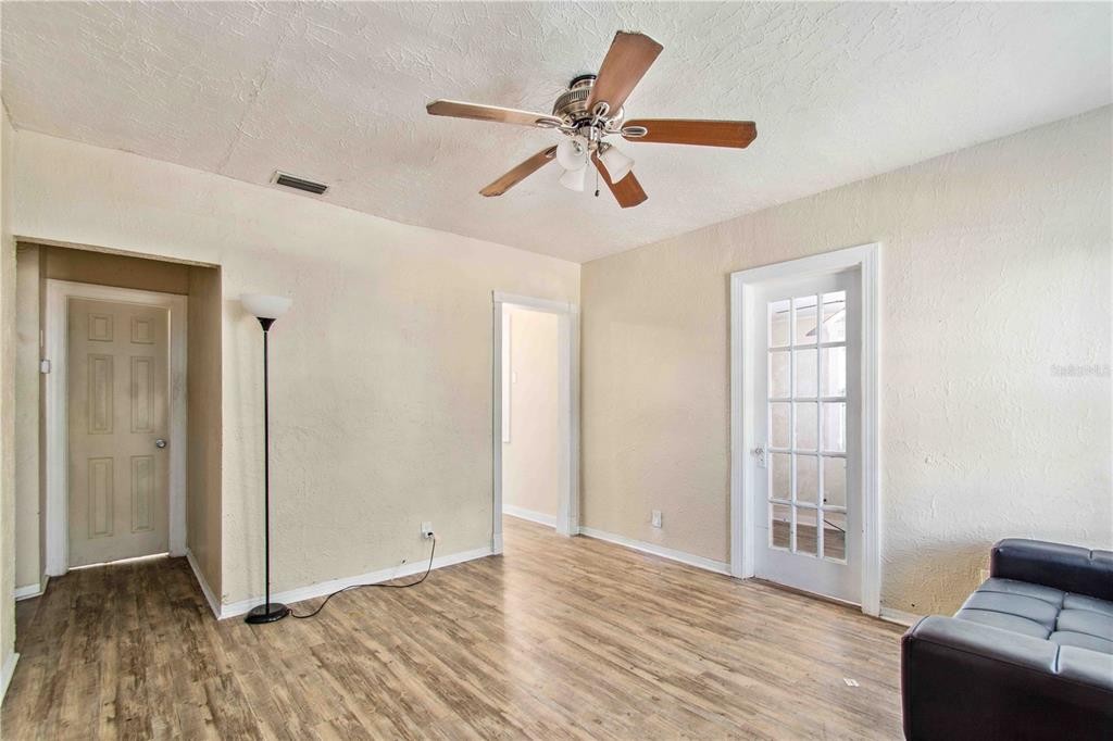 A living room features wood-look flooring, a ceiling fan, and two interior doorways — 4411 3RD AVENUE S, ST PETERSBURG, FL