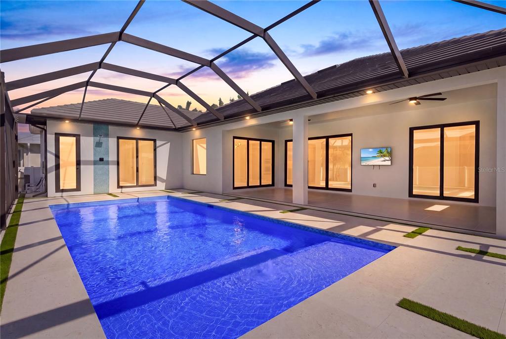 A swimming pool sits on a patio enclosed by a screened lanai next to a house — 2739 SW 42ND LANE, CAPE CORAL, FL