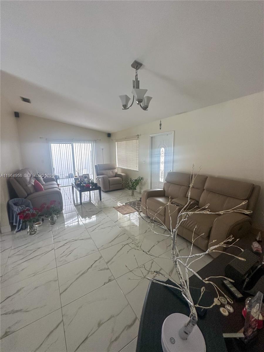 A living room features white marble-look tile floors, two leather sofas, and a light fixture — 14759 SW 82nd St, Miami FL 33193, MIAMI, FL